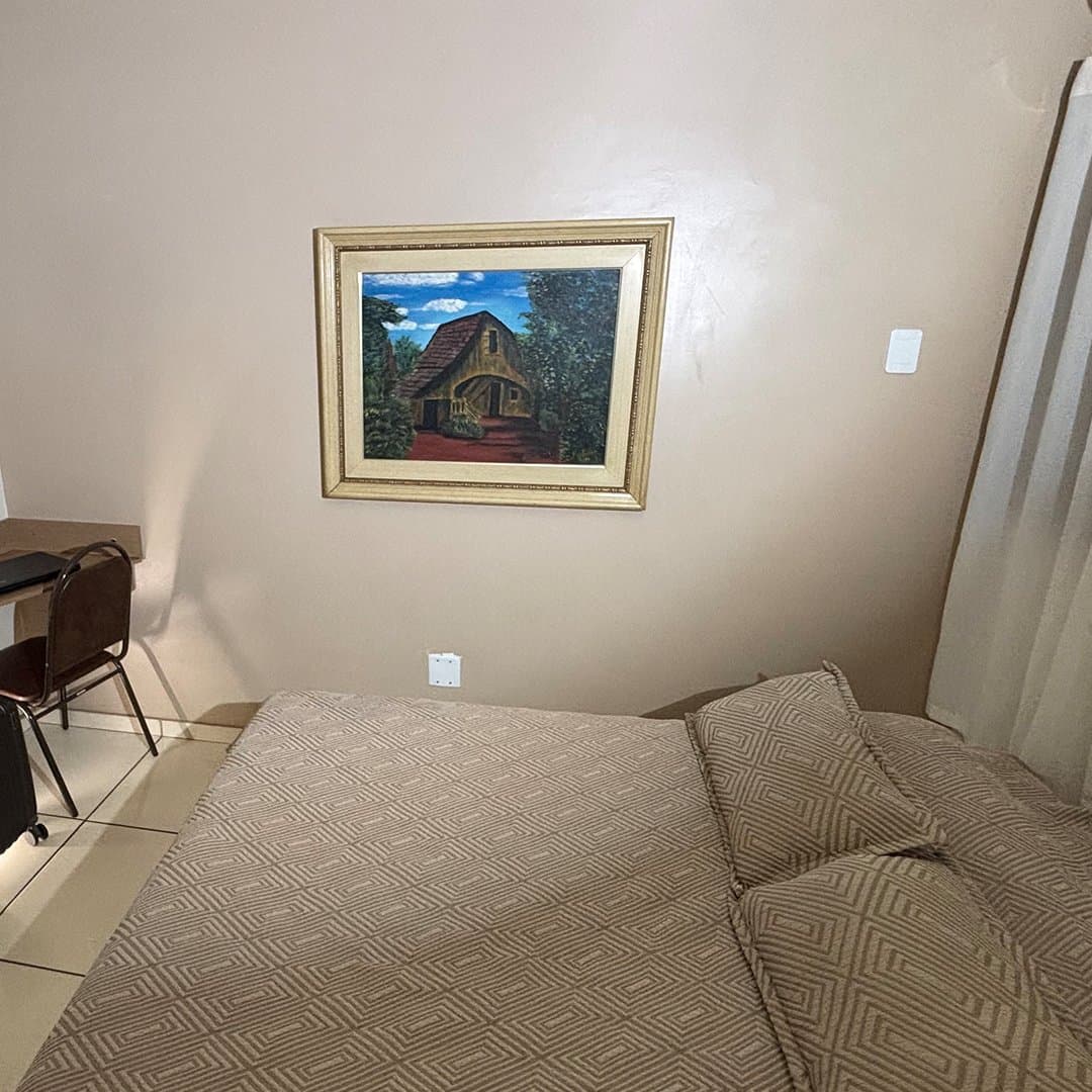 Cama de casal e mesa de trabalho no apartamento Luxo do Hotel Galli