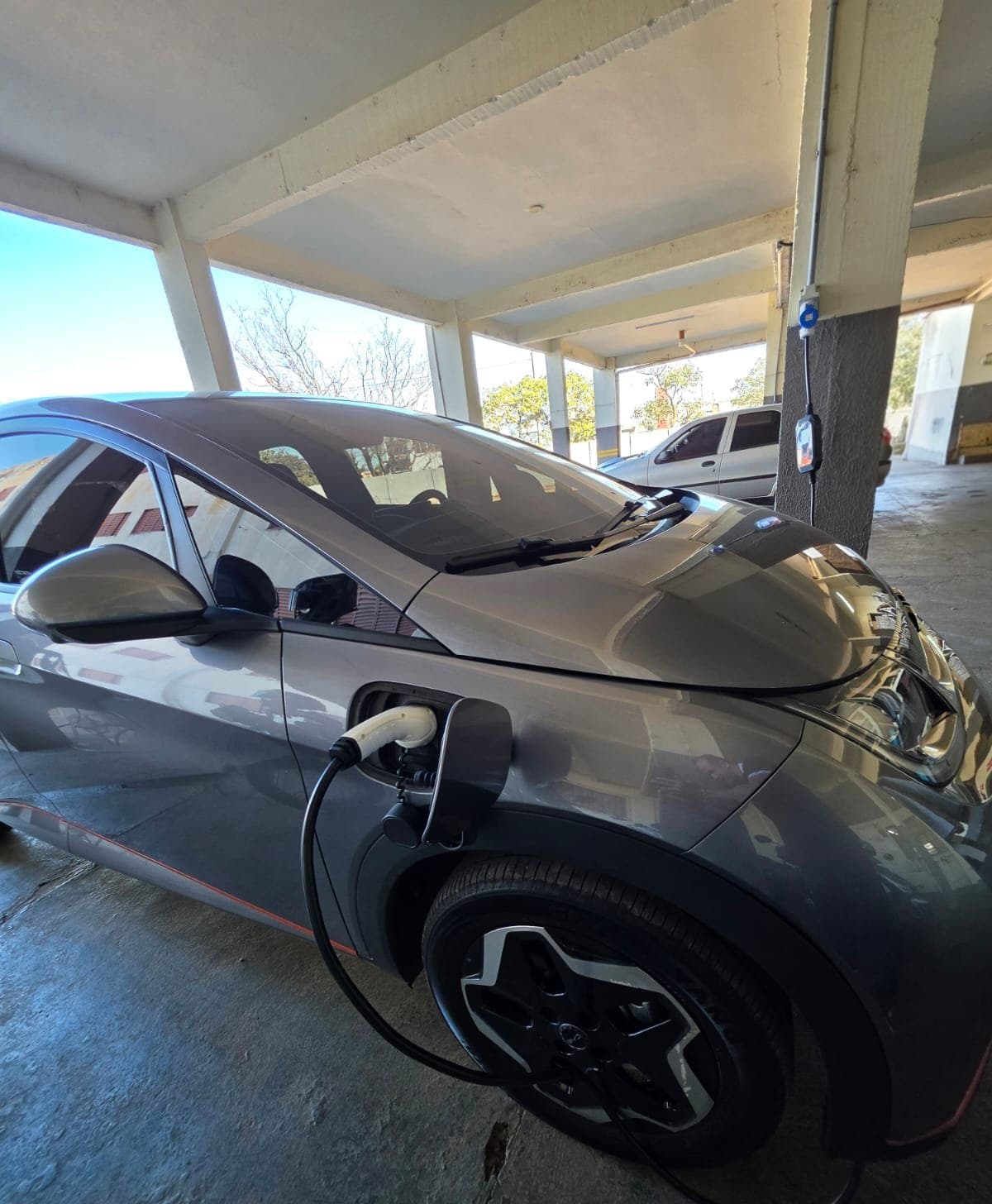Cabo do carregador conectado ao carro elétrico, na garagem do Hotel Galli